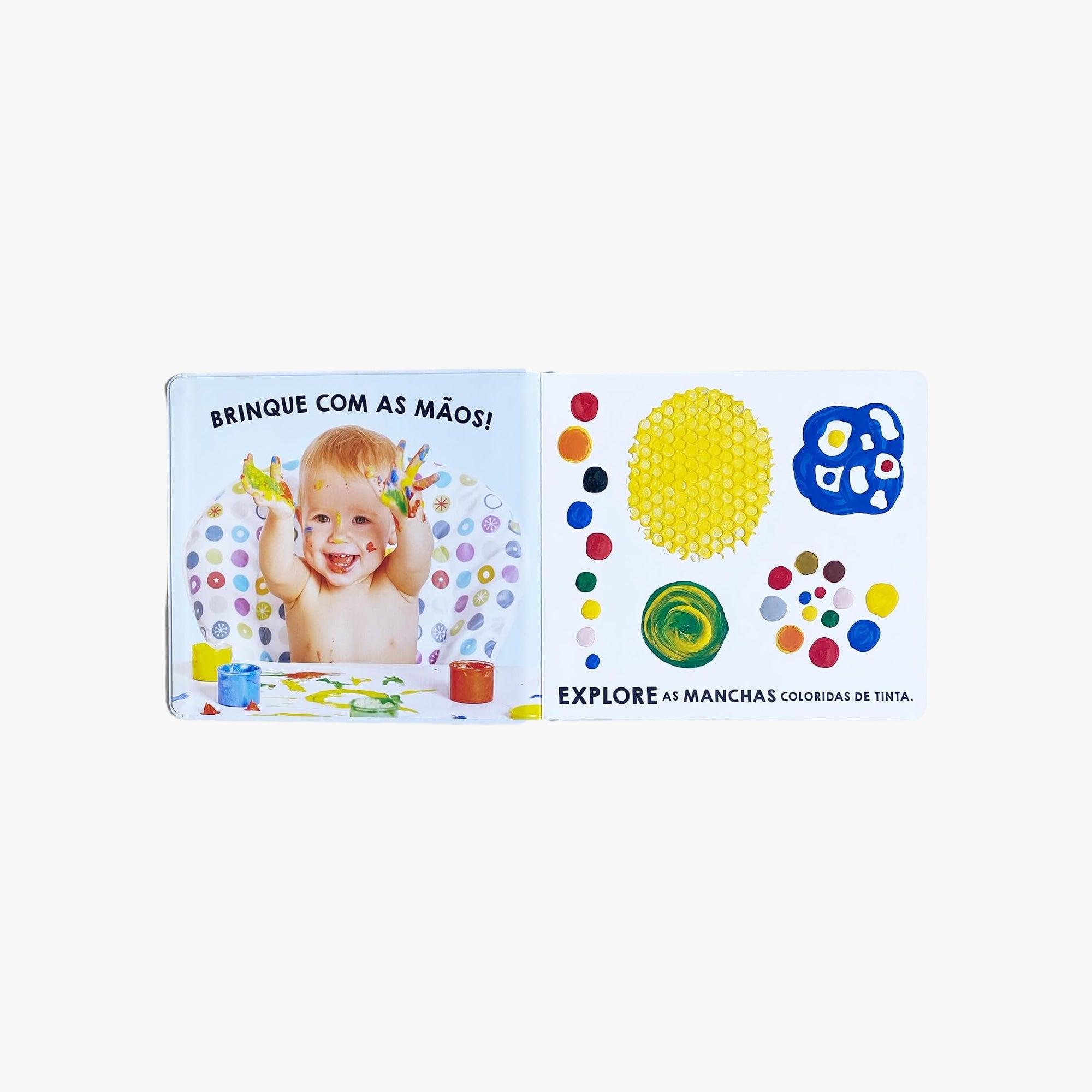 Bebê explorando o livro Ver, Tocar, Sentir com as mãos